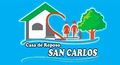 Logotipo de Casa de Reposo San Carlos con una casa, dos personas y un &aacute;rbol verde sobre un fondo azul.