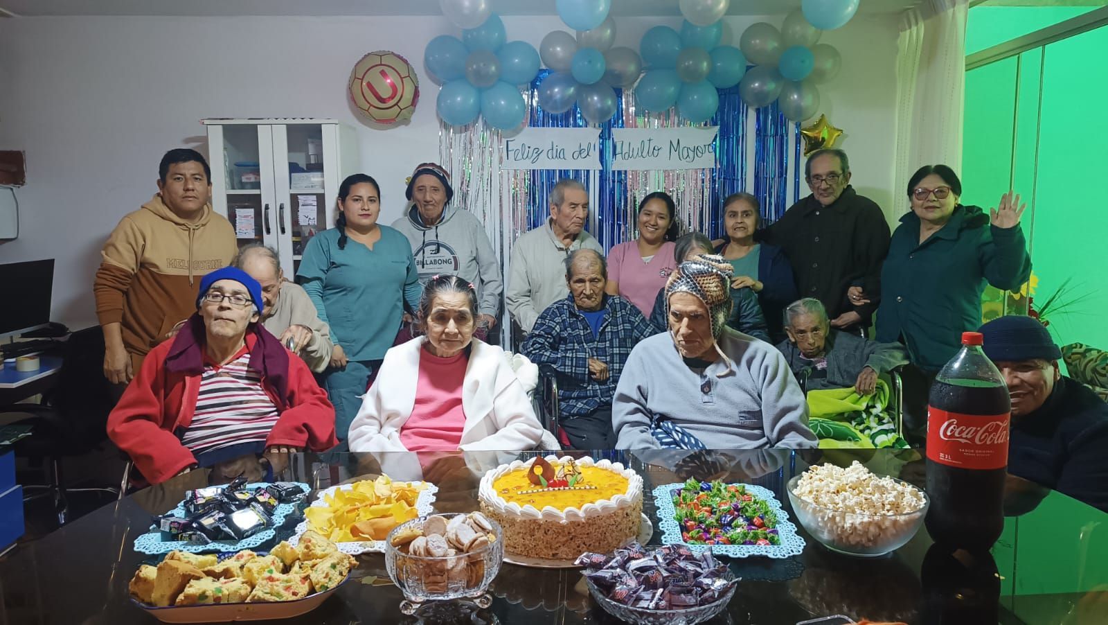 Un grupo de personas se reunió detrás de una mesa con frutas y postres en una celebración festiva en el interior.