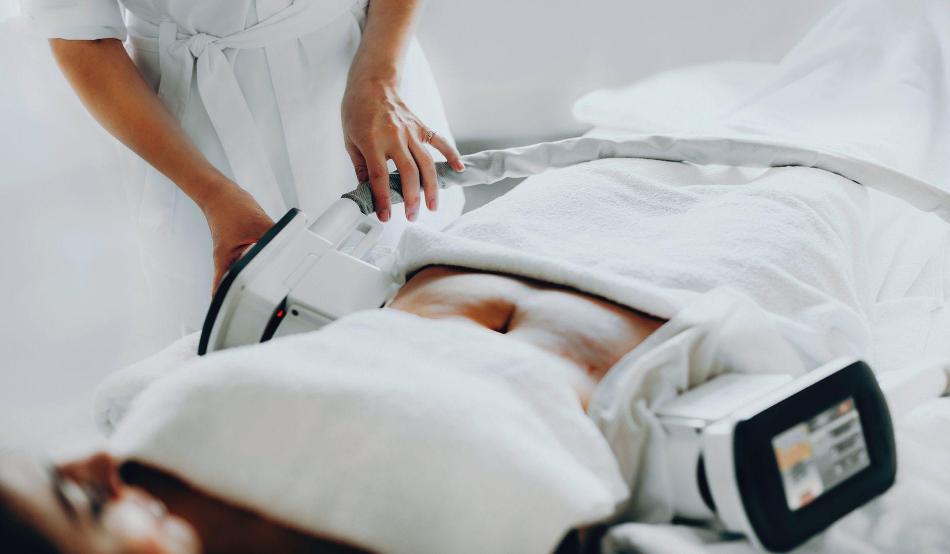 Person undergoing an ultrasound scan on a medical table, with a technician holding the probe