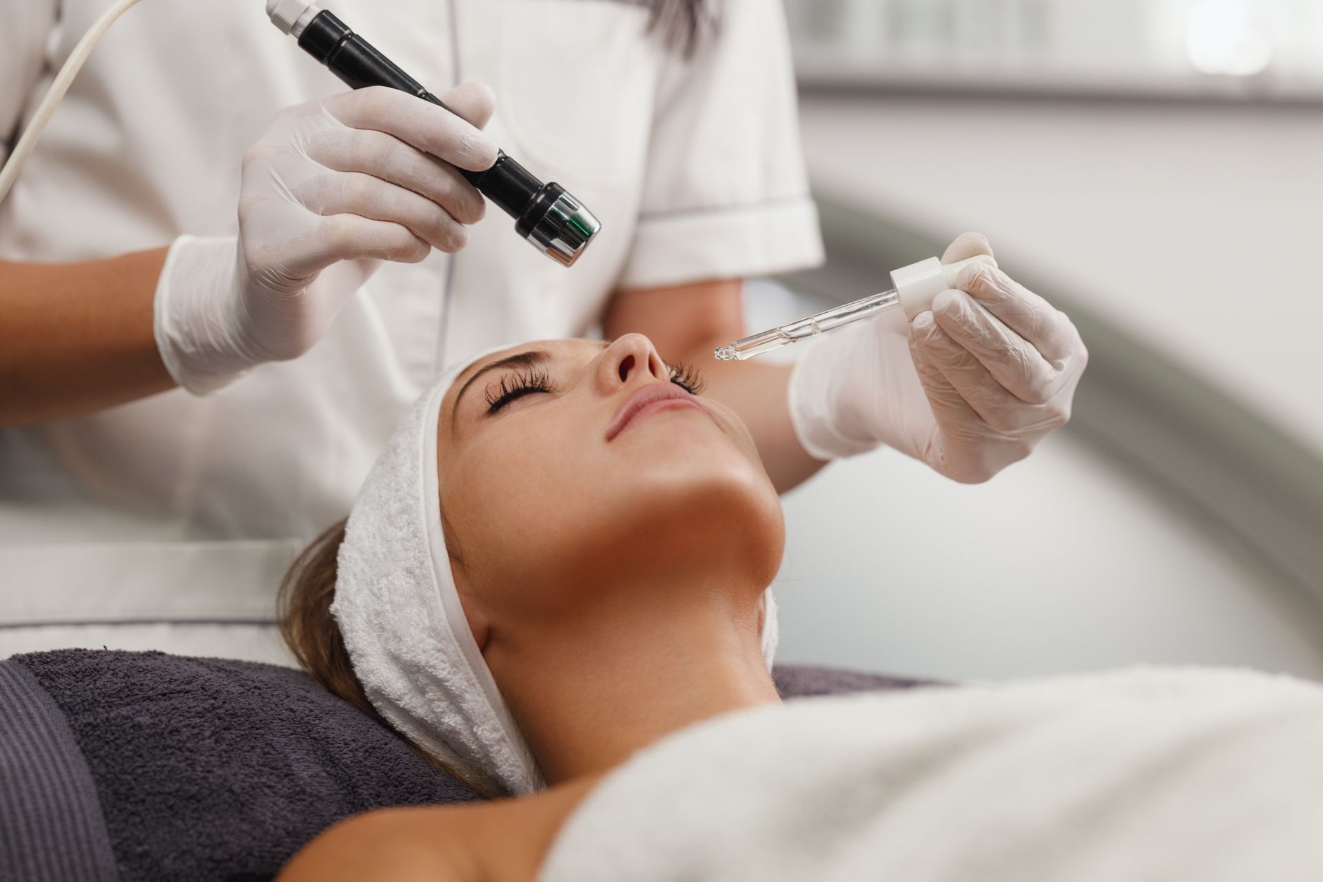 Facial treatment with a handheld device applied to a woman lying on a spa bed