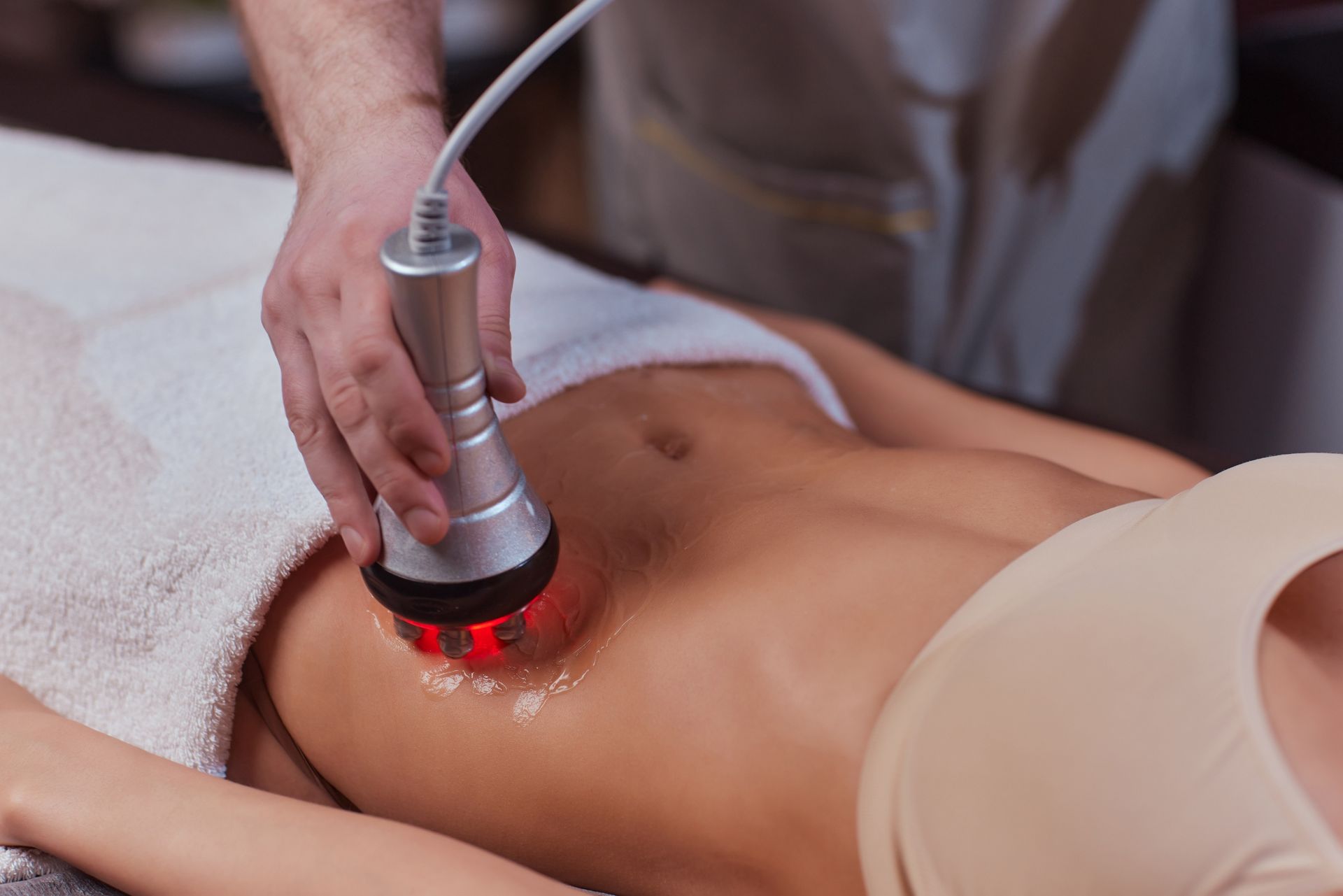 Laser treatment being applied to a person’s bare abdomen in a spa or clinic setting