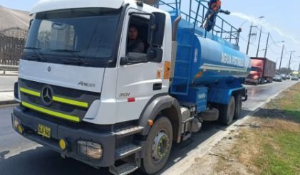Camión cisterna blanco y azul estacionado al borde de la carretera con un conductor visible en la cabina.