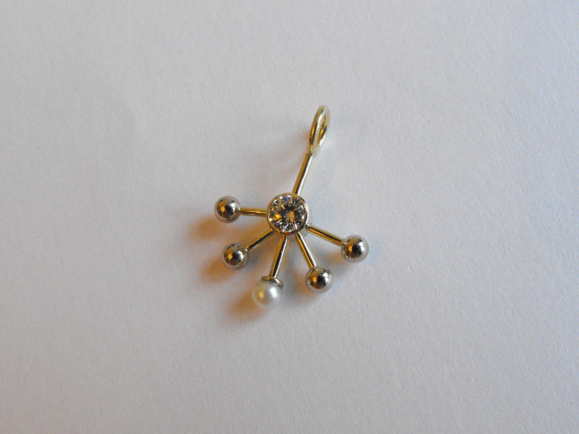 Gouden hanger met gewonnen diamant. De witgouden bolletjes en parel staan voor de kinderen.