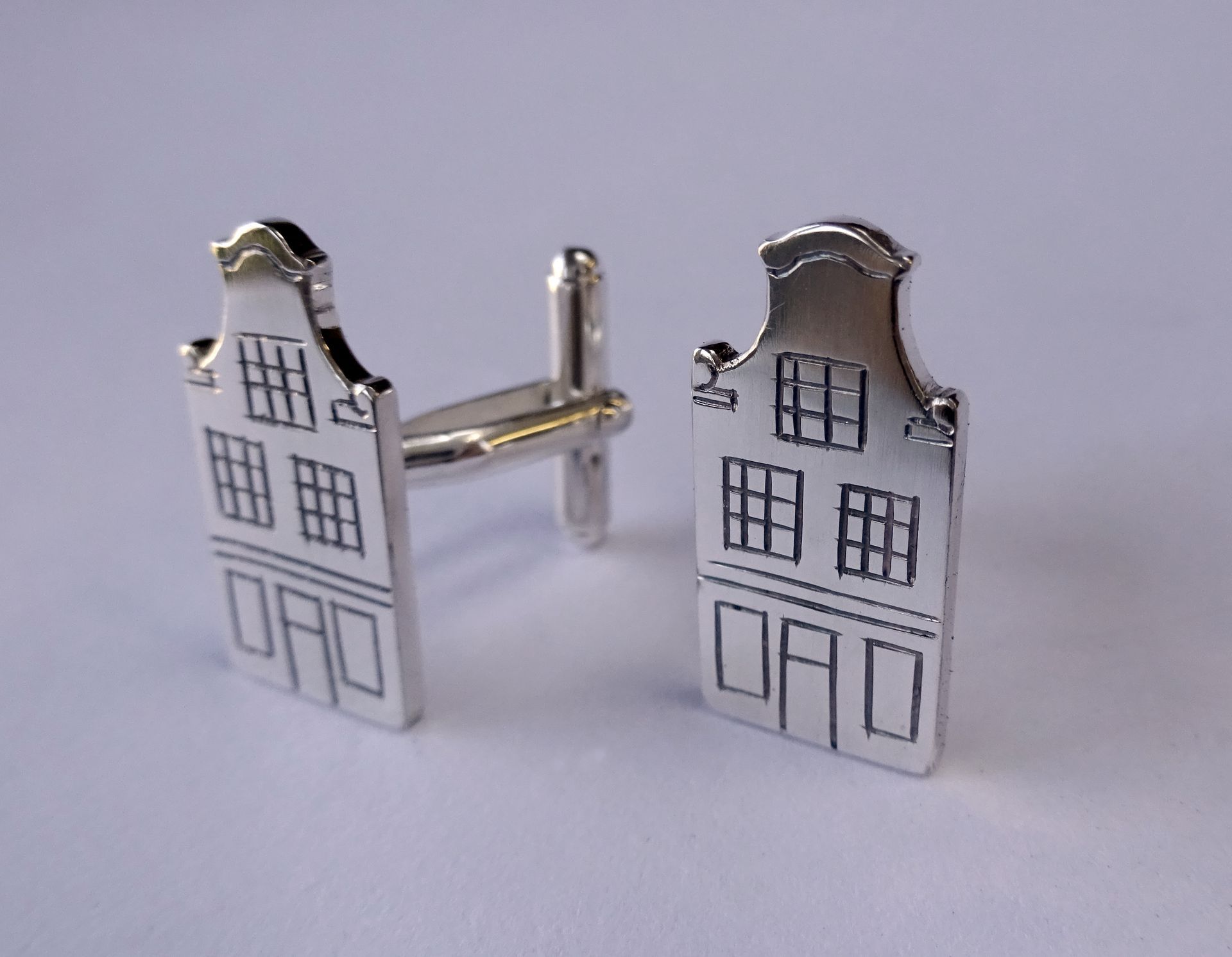 Zilveren manchetknopen van een huisje met een klokgevel.