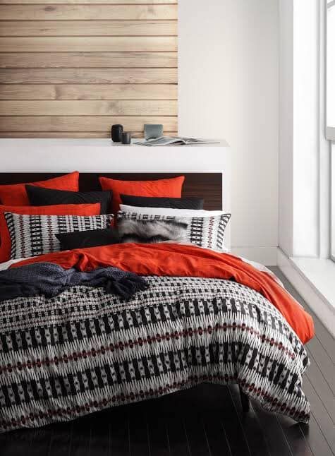 Bed With Patterned Comforter, Orange and Black Pillows — Enterprise Electrics NT Pty Ltd in Tennant Creek, NT