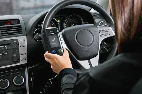 Person Using a Handheld Device in a Car Display Shows a Checkmark — All Coast Auto Solutions in Noosaville, QLD