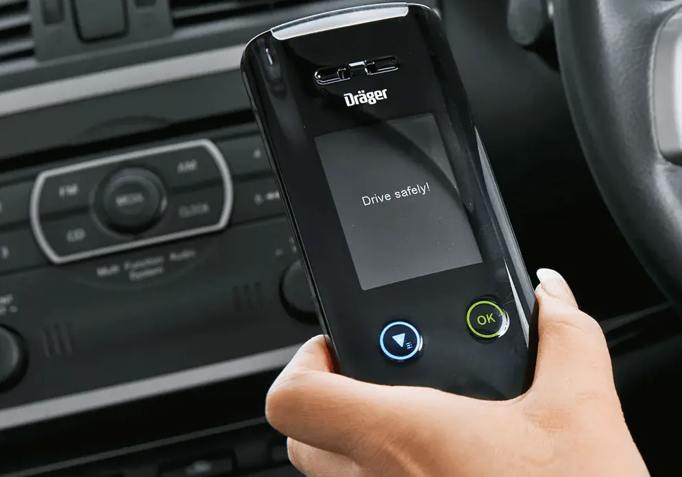 Hand Holding a Black Draeger Breathalyzer in a Car — All Coast Auto Solutions in Noosaville, QLD