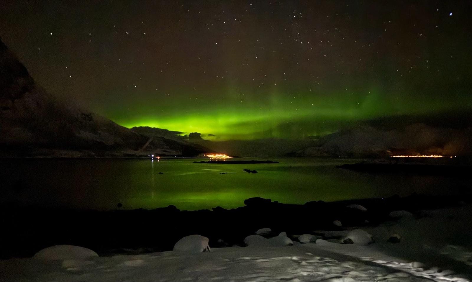 The aurora borealis is shining over a lake at night.