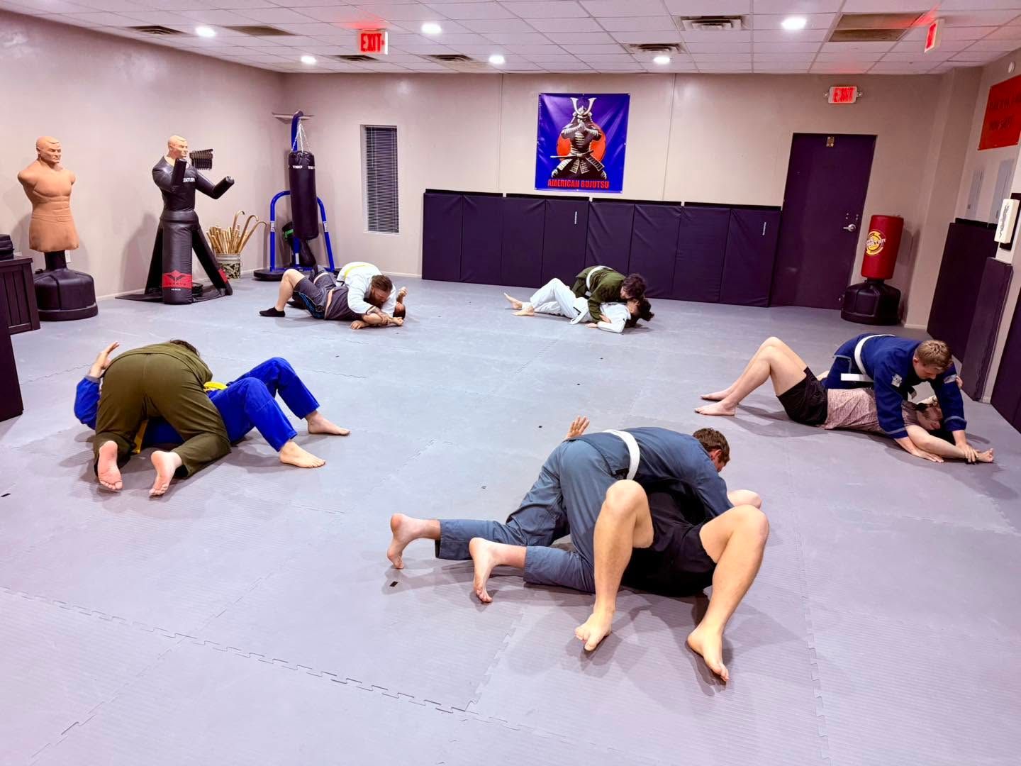 People grappling on mats in a martial arts training room