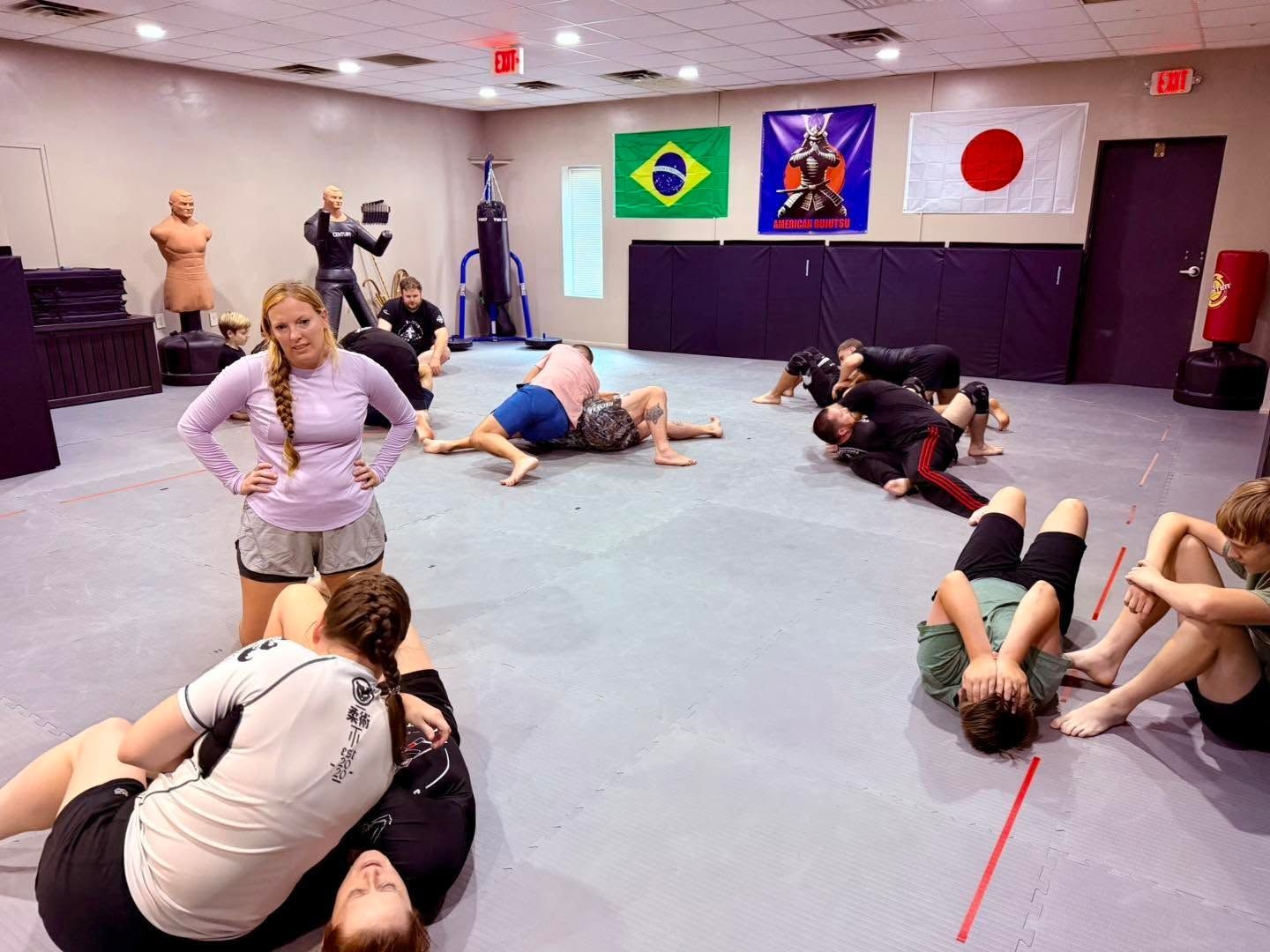 People exercising on mats in a studio with Brazil and Japan flags on the wall