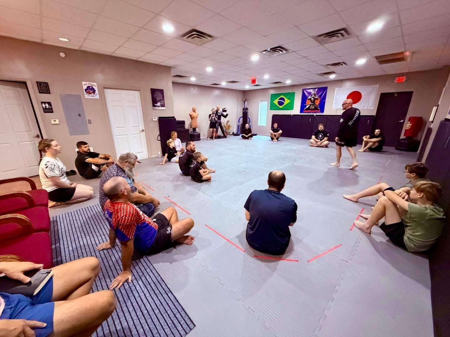 People seated in a room watching an indoor presentation with a large screen and flags.