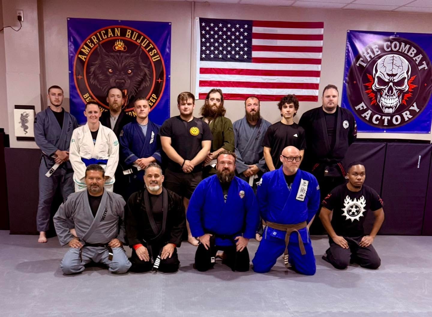 Group portrait of martial arts students and instructors in a dojo with U.S. flag and gym banners