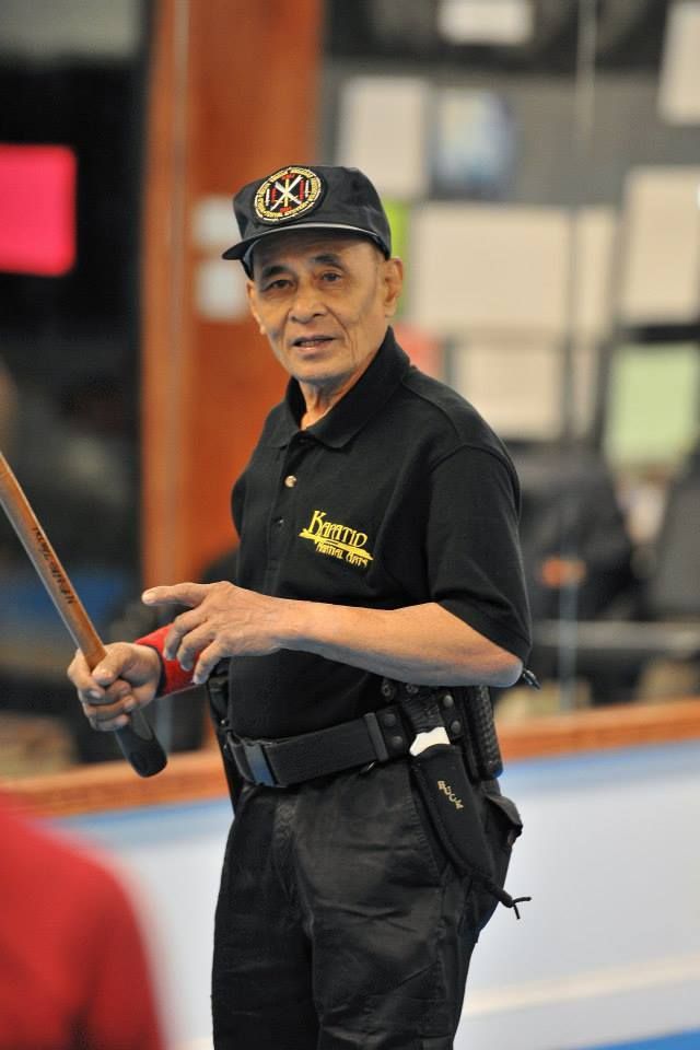Uniformed security guard holding a baton indoors, standing alert near a rink