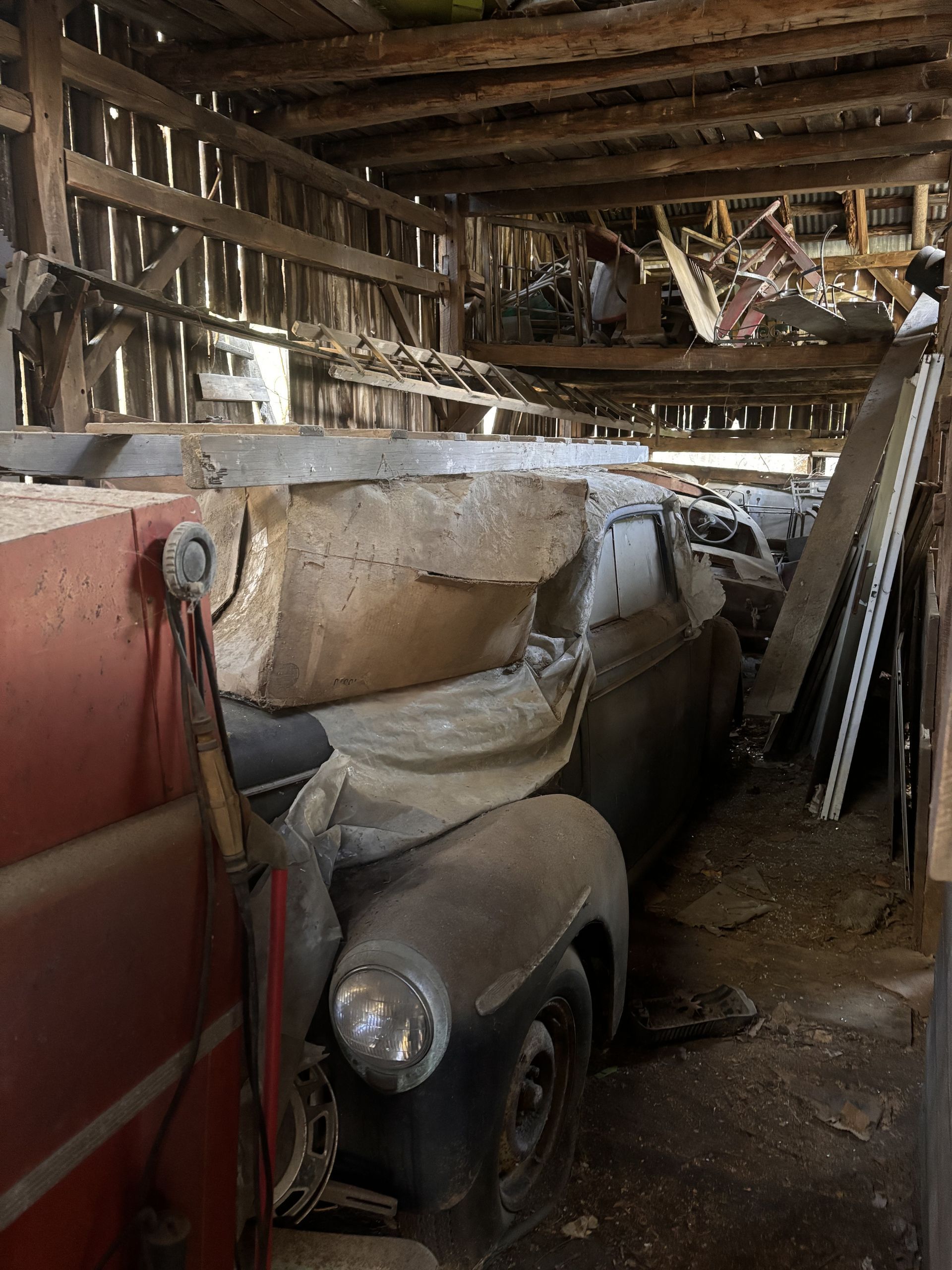 A bunch of old cars are sitting in a barn.