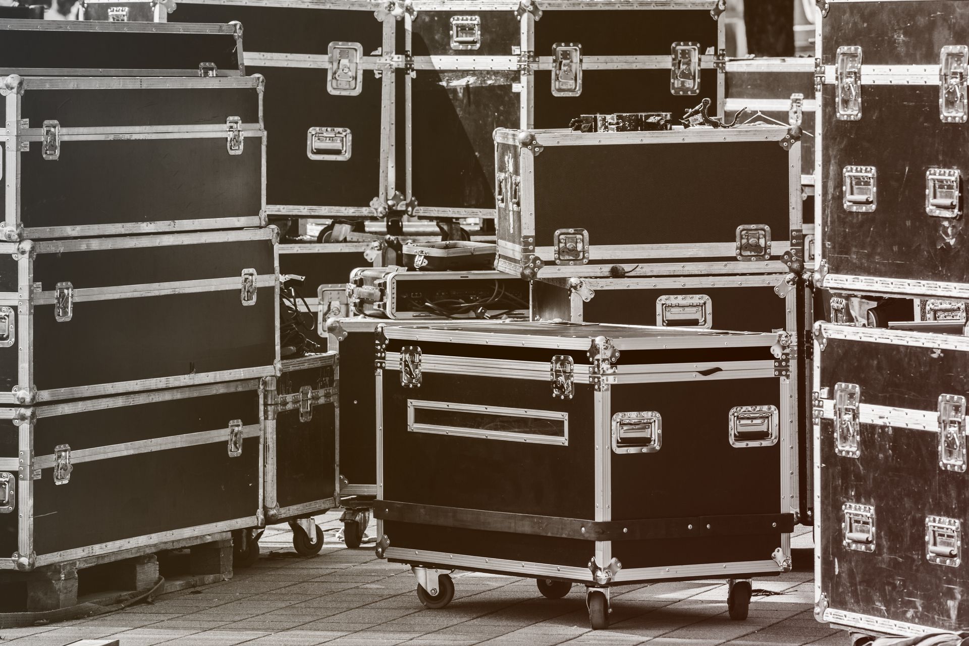 Black road cases stacked on pallets and wheeled cases, ready for transport.