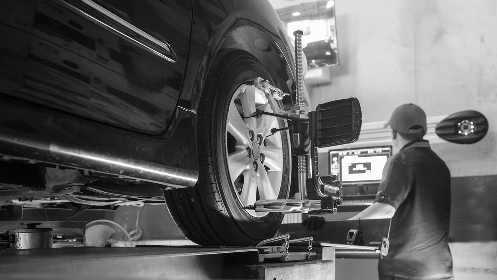 A Man Is Adjusting The Alignment Of A Car In A Garage — Advanced Auto Tech In Port Macquarie, NSW