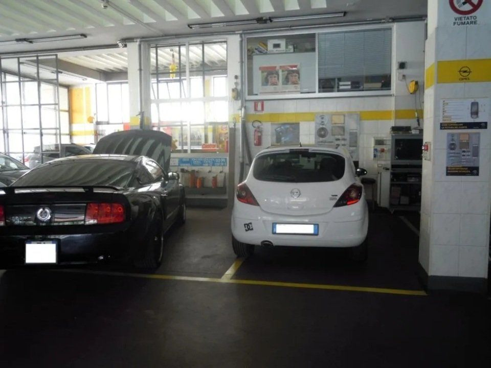 Due auto parcheggiate in un luminoso parcheggio coperto accanto a un distributore automatico di biglietti.