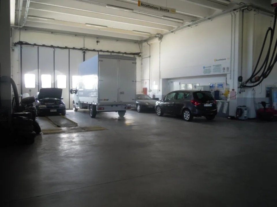 Ampio garage con diverse auto parcheggiate e un furgone bianco all'interno.
