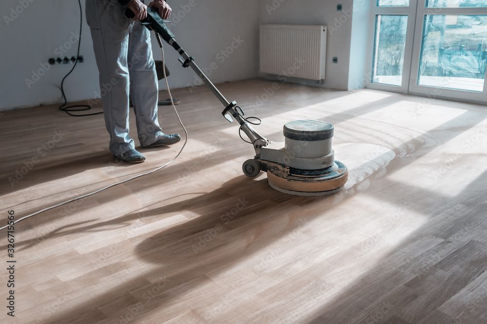 Un homme polit un parquet avec une machine.