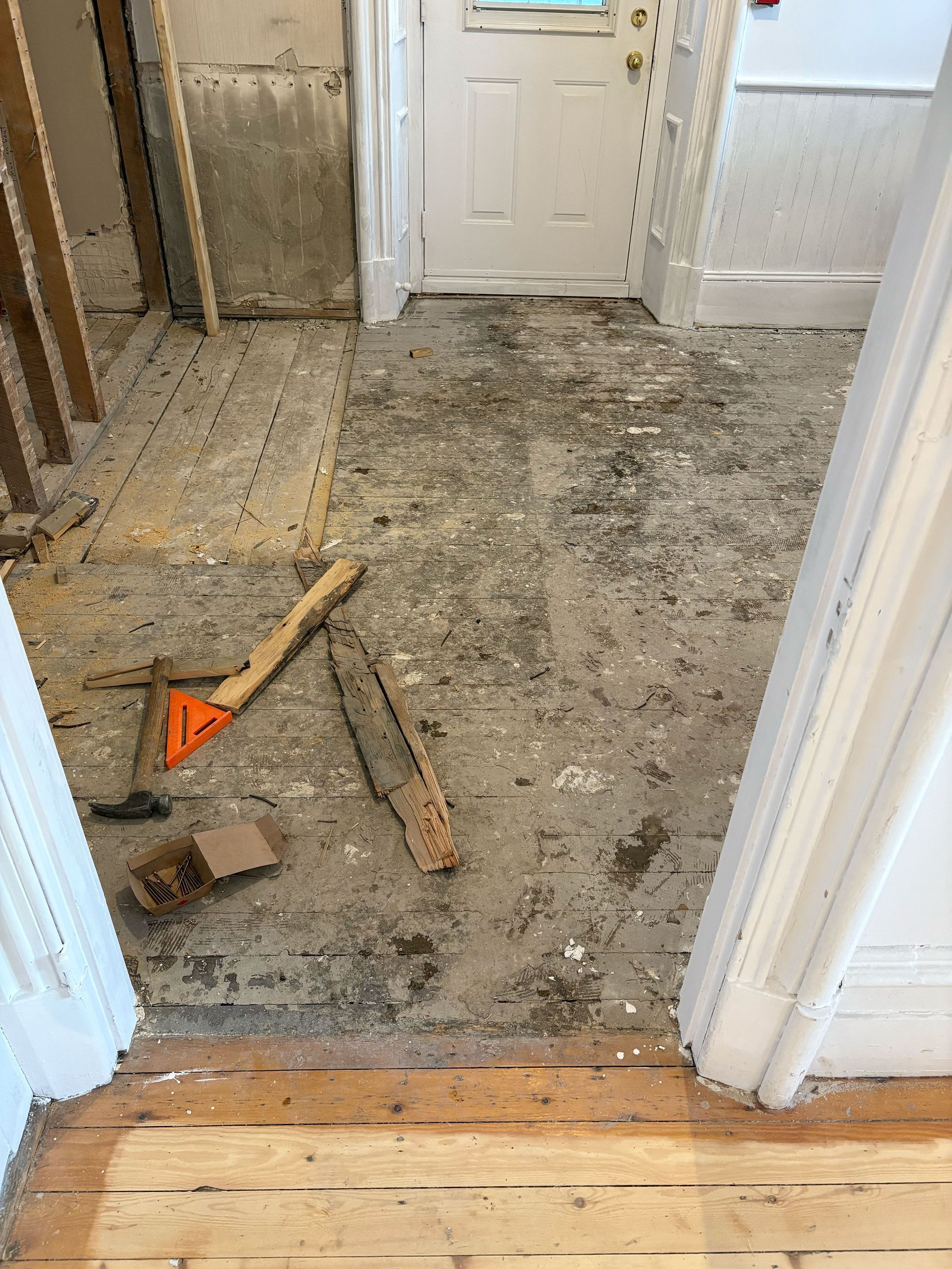 Une pièce avec un plancher en bois et une porte qui est en cours de rénovation.