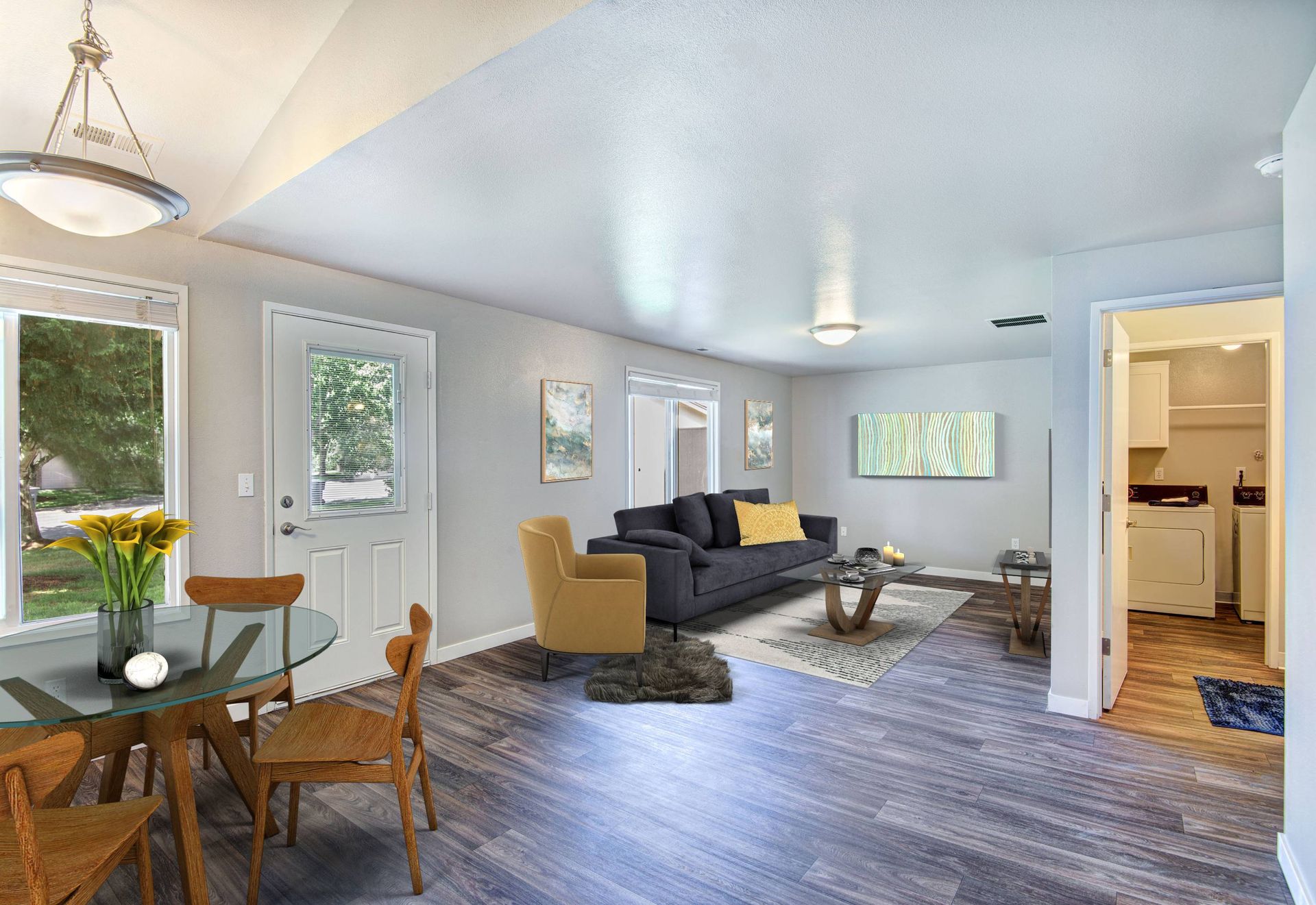 Open living area with sofa, chairs, coffee table, dining table, and adjacent laundry area.