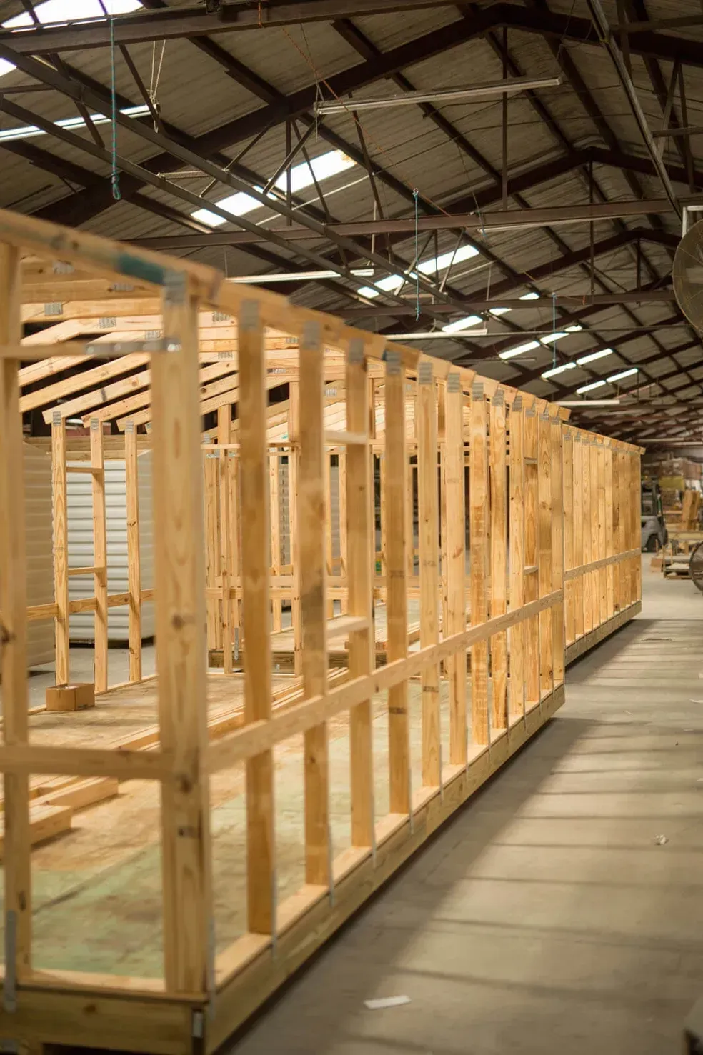 Wooden frame of a building under construction inside a warehouse.
