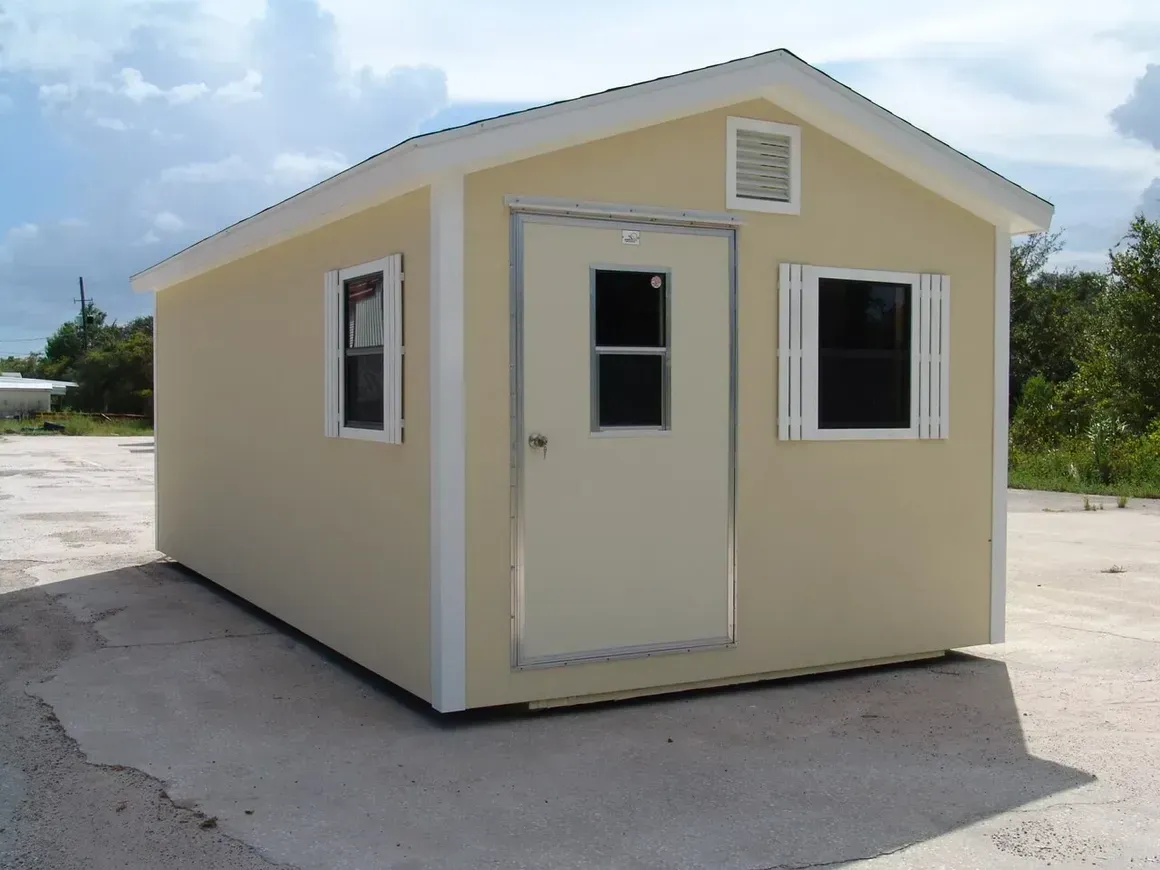 Tan prefab cabin with a white door, windows, and trim.