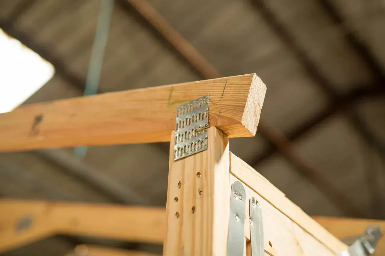 Wooden beams joined with metal brackets under a roof structure.