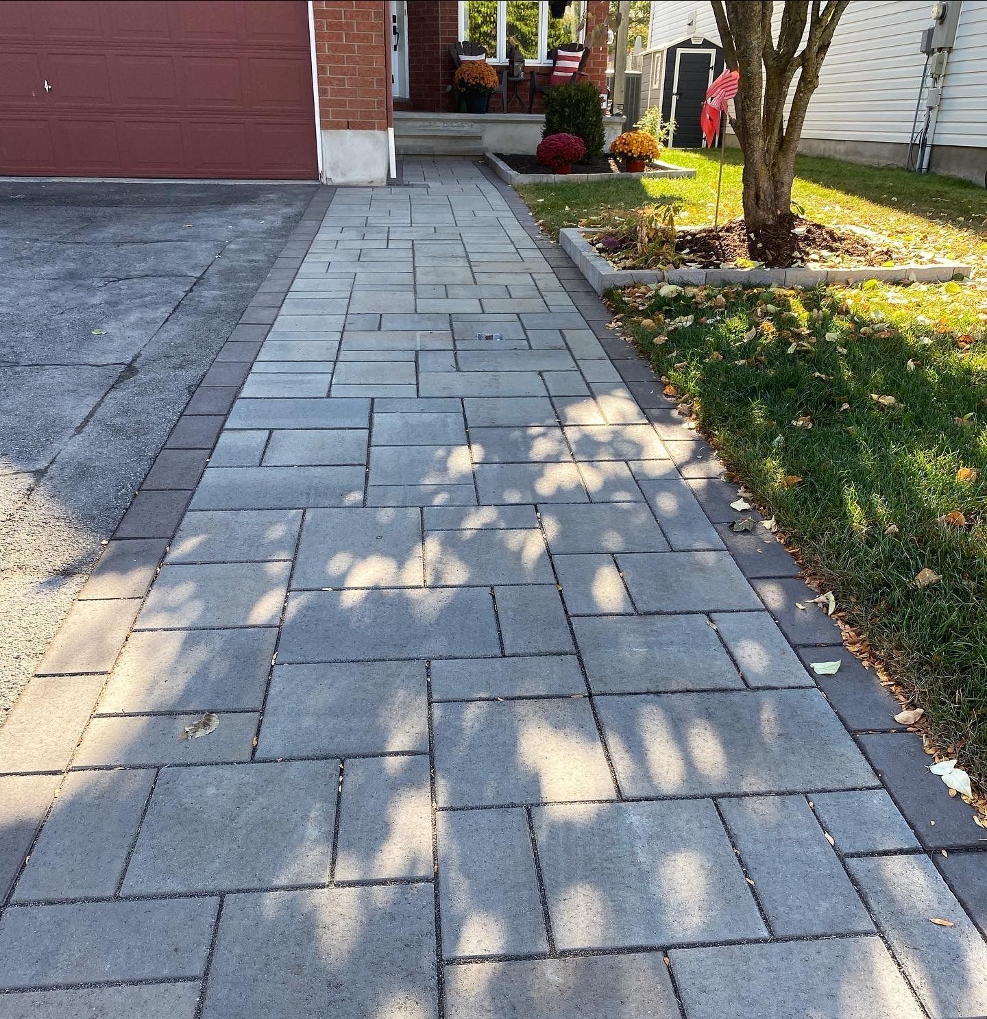 a brick walkway leading to a house with a red garage door