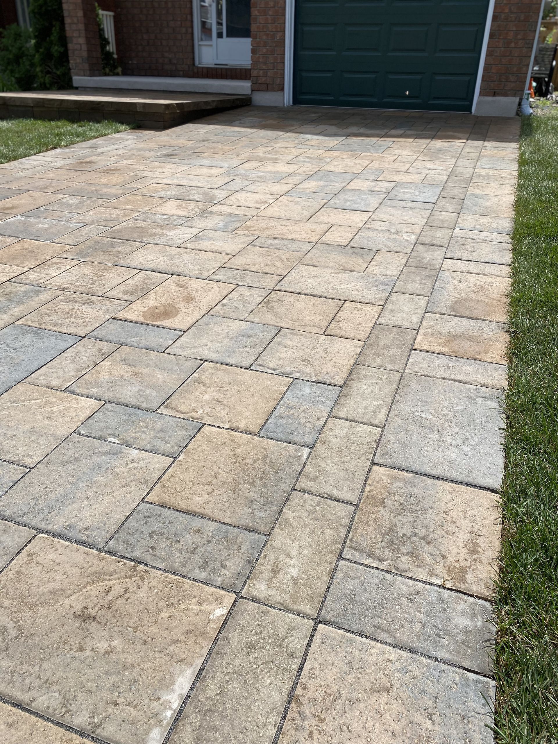 a driveway with a green garage door in the background