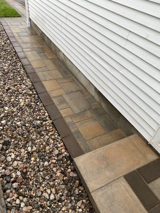 a stone walkway along the side of a house