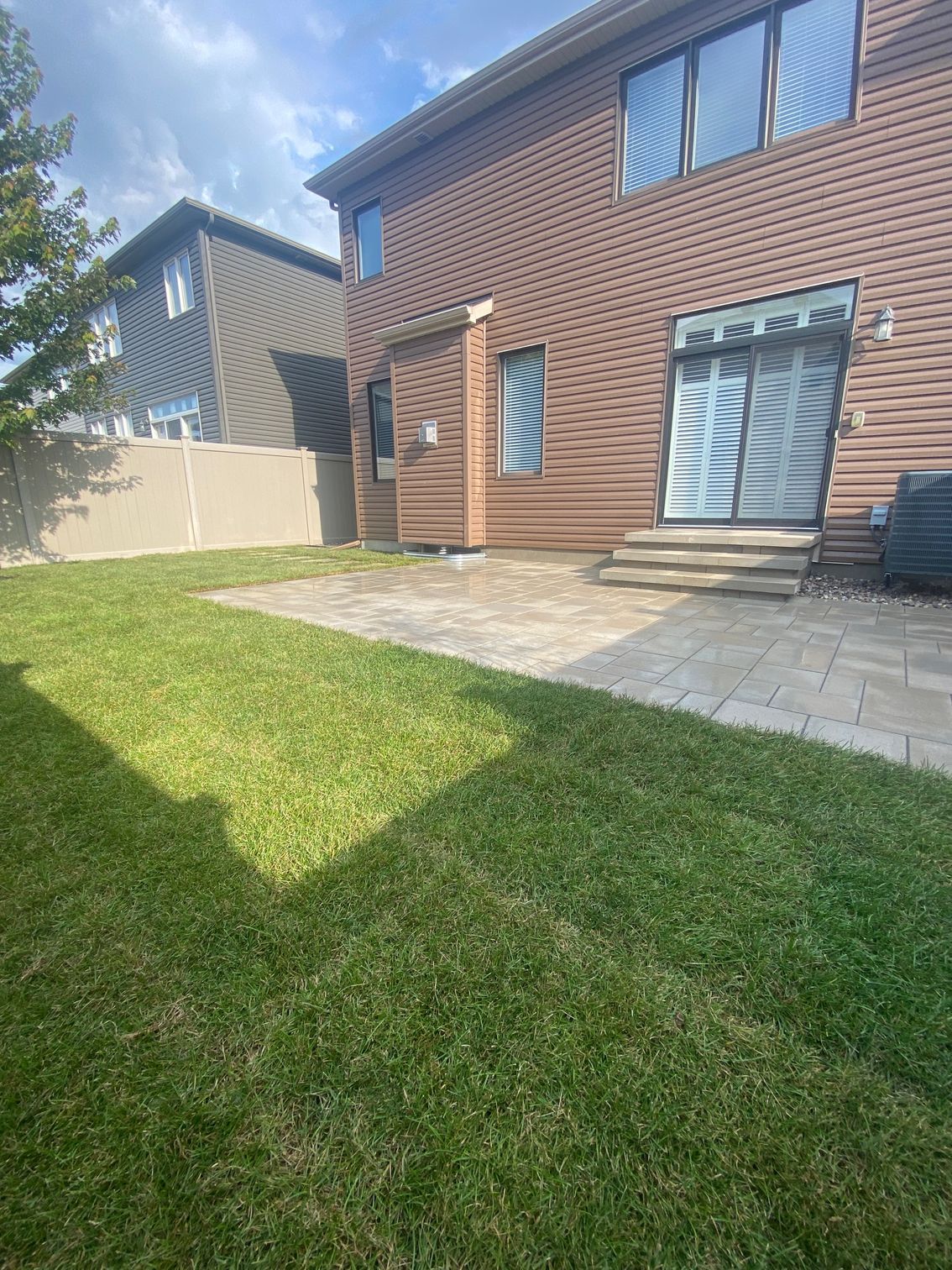 the backyard of a house with a large lawn and a patio .