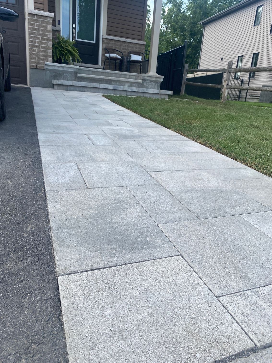 a walkway leading to a house with a car parked on the side of it .