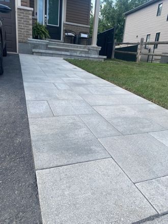 a walkway leading to a house with a car parked on the side of it .