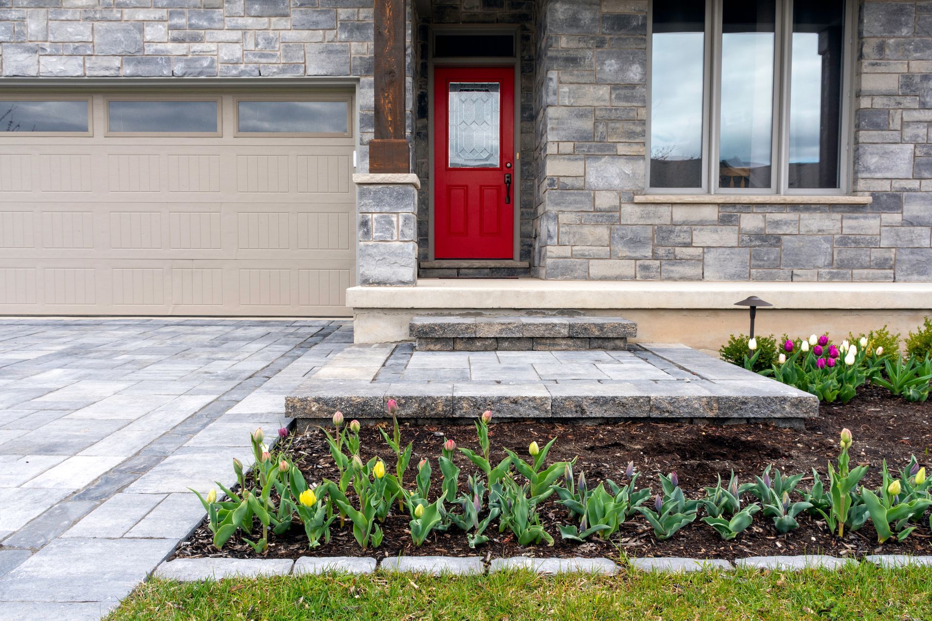 the front of a house with a red door and a walkway leading to it .