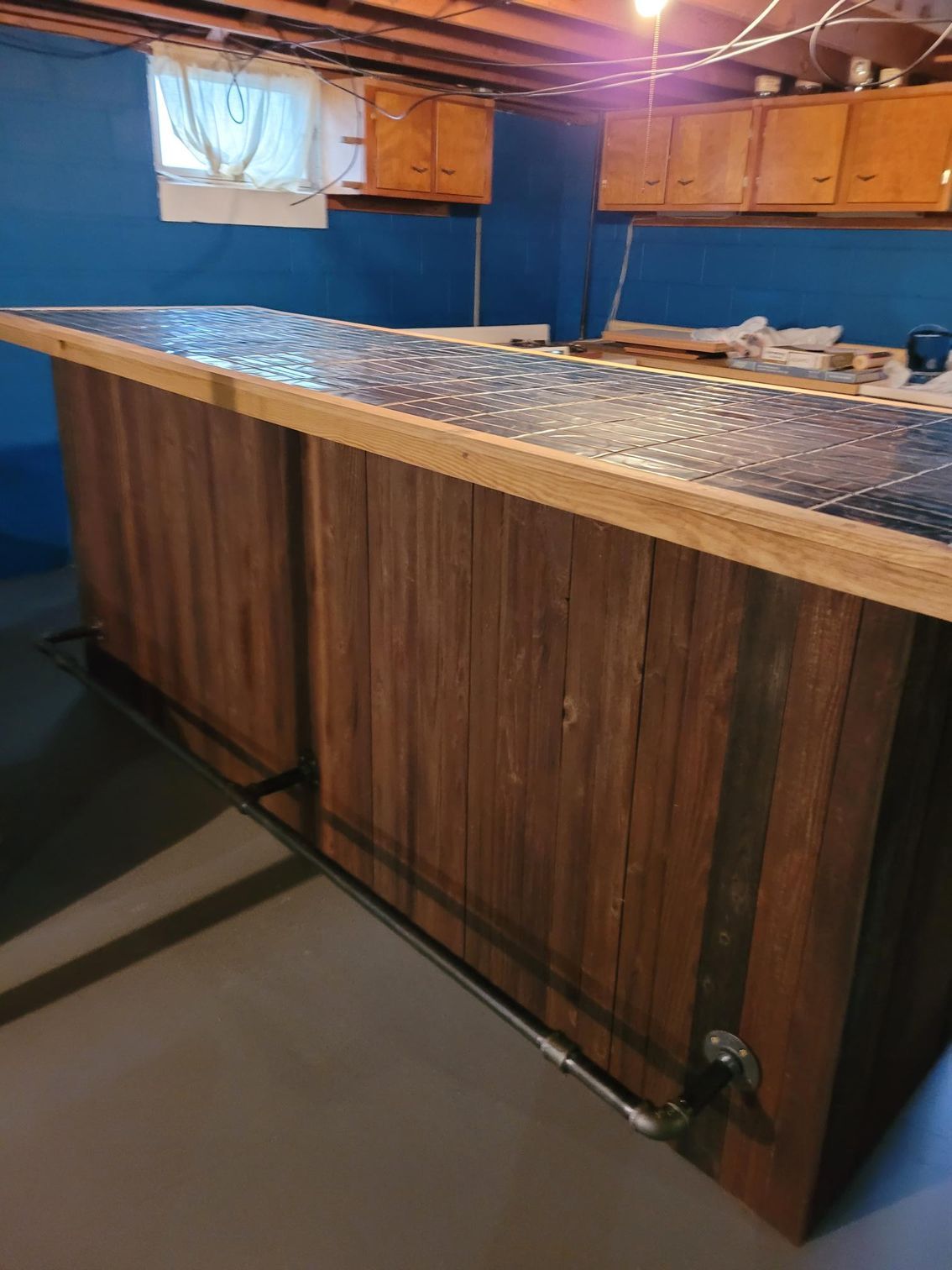 Basement bar with blue walls, wood cabinets, and a long speckled countertop.