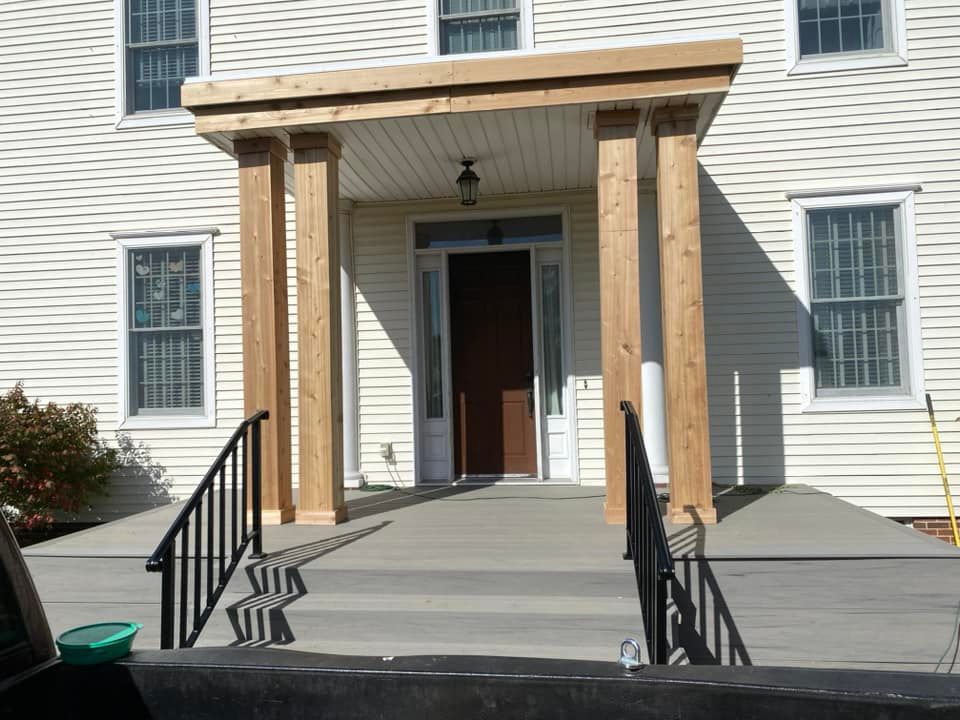 Accessible entrance with a ramp, handrails, and covered doorway on a white building