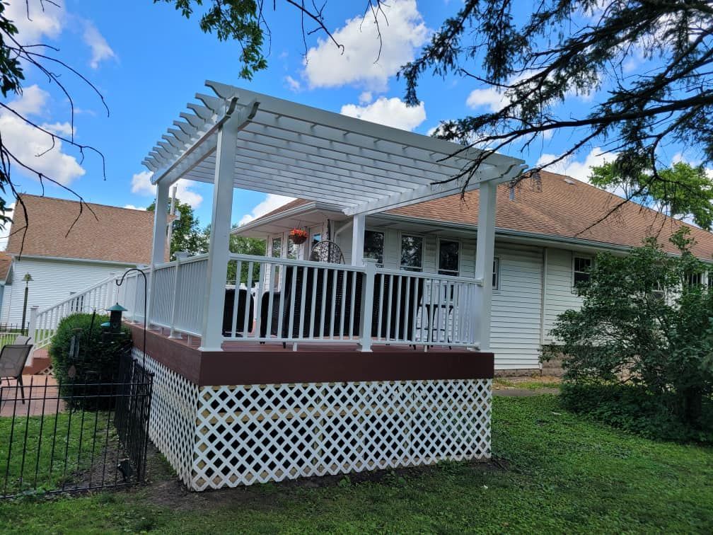 White porch gazebo on a grassy yard beside a house, with lattice skirting and a blue sky overhead