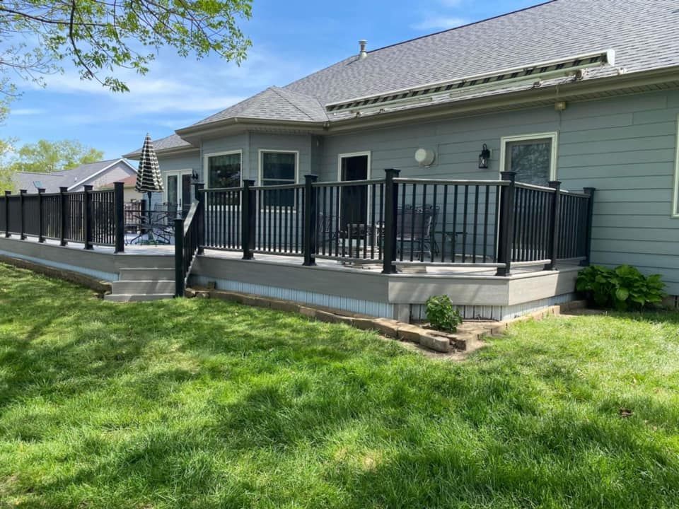 House with black-railed porch and green lawn on a sunny day