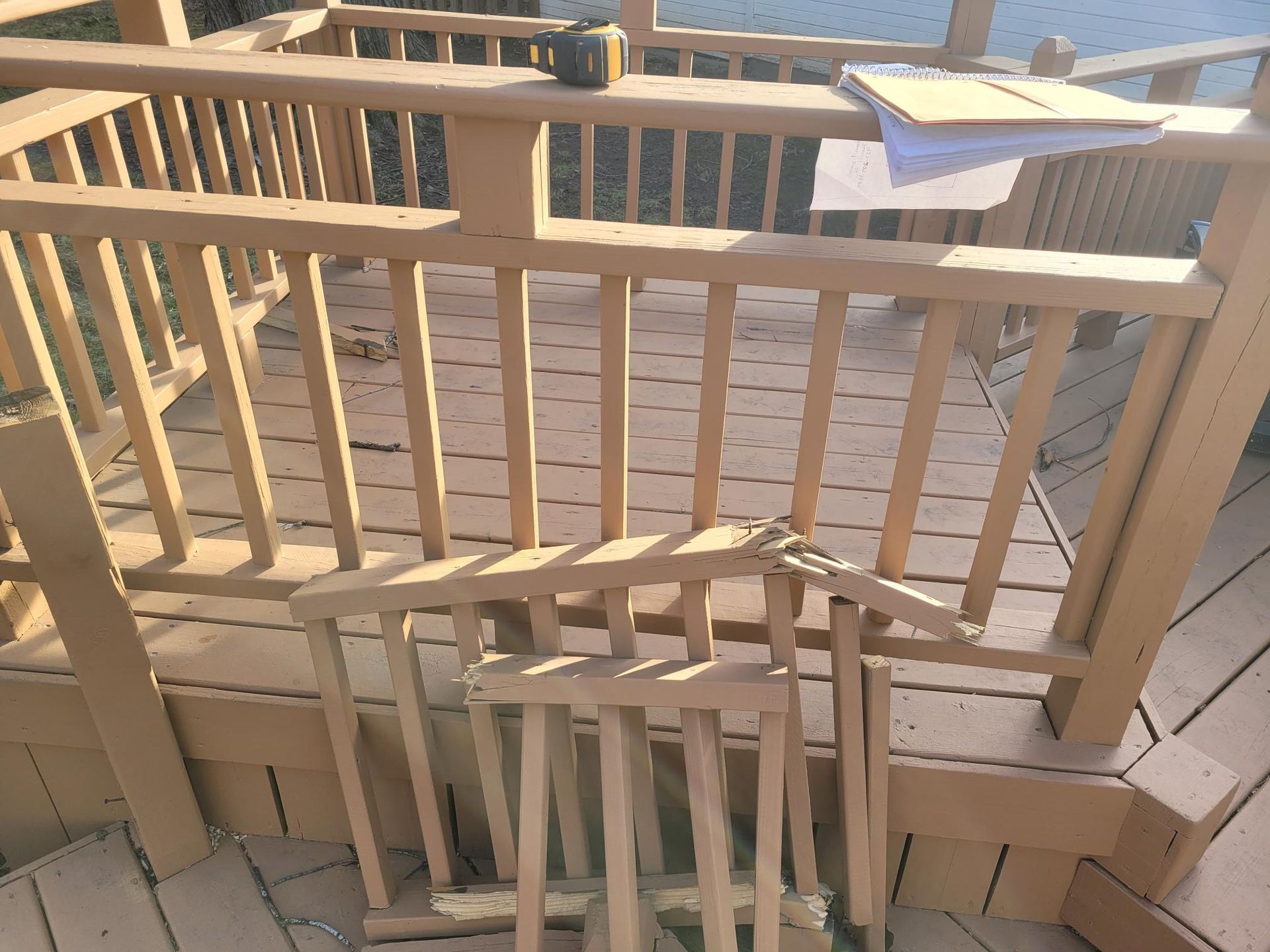 Broken wooden deck railing with a loose gate panel and a towel draped over the fence.