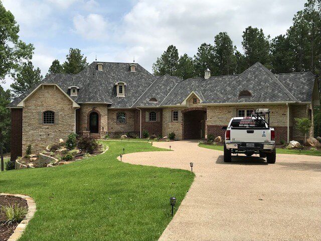 A white truck is parked in front of a large house