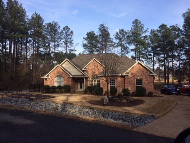 A large brick house sits in the middle of a forest