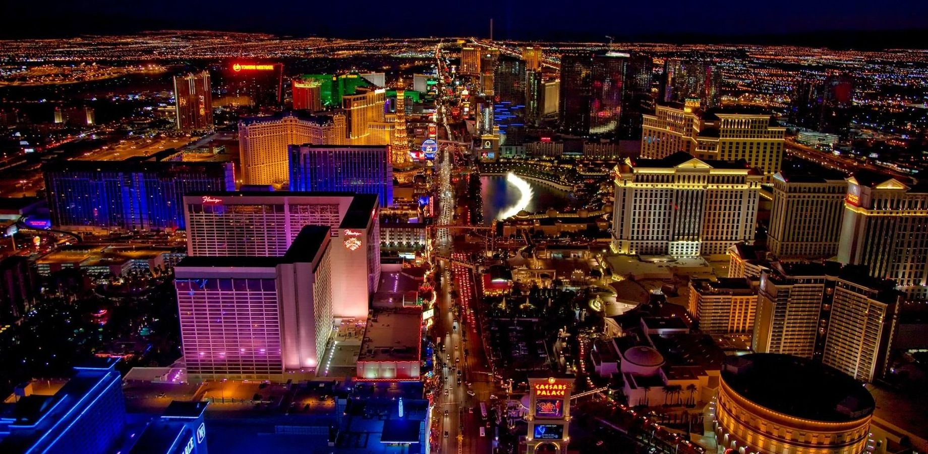 An aerial view of a city at night with lots of buildings lit up.