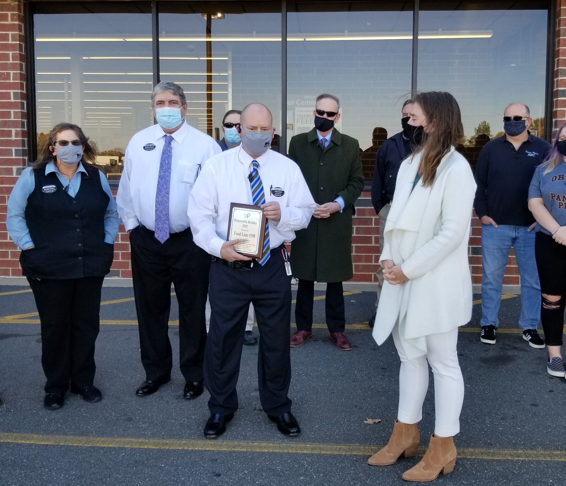 A group of people wearing face masks stand in front of a building