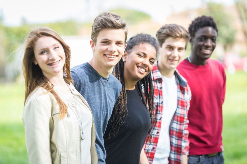 A group of young people are posing for a picture in a park.