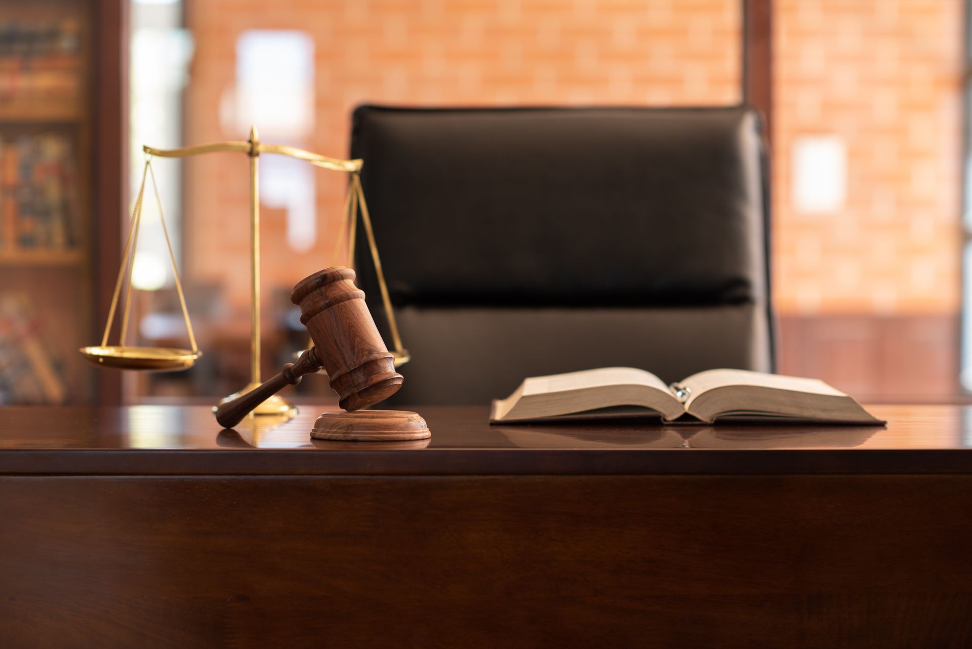Judge’s gavel and scales on a desk with an open book in a courtroom or law office. Judge’s gavel and scales on a desk with an open book in a courtroom or law office.