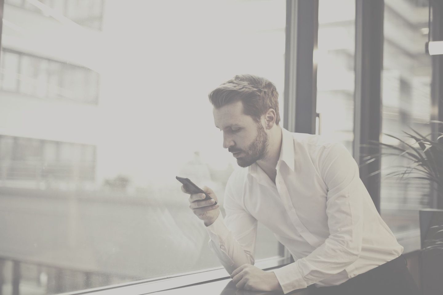 A man is sitting at a table looking at his cell phone.