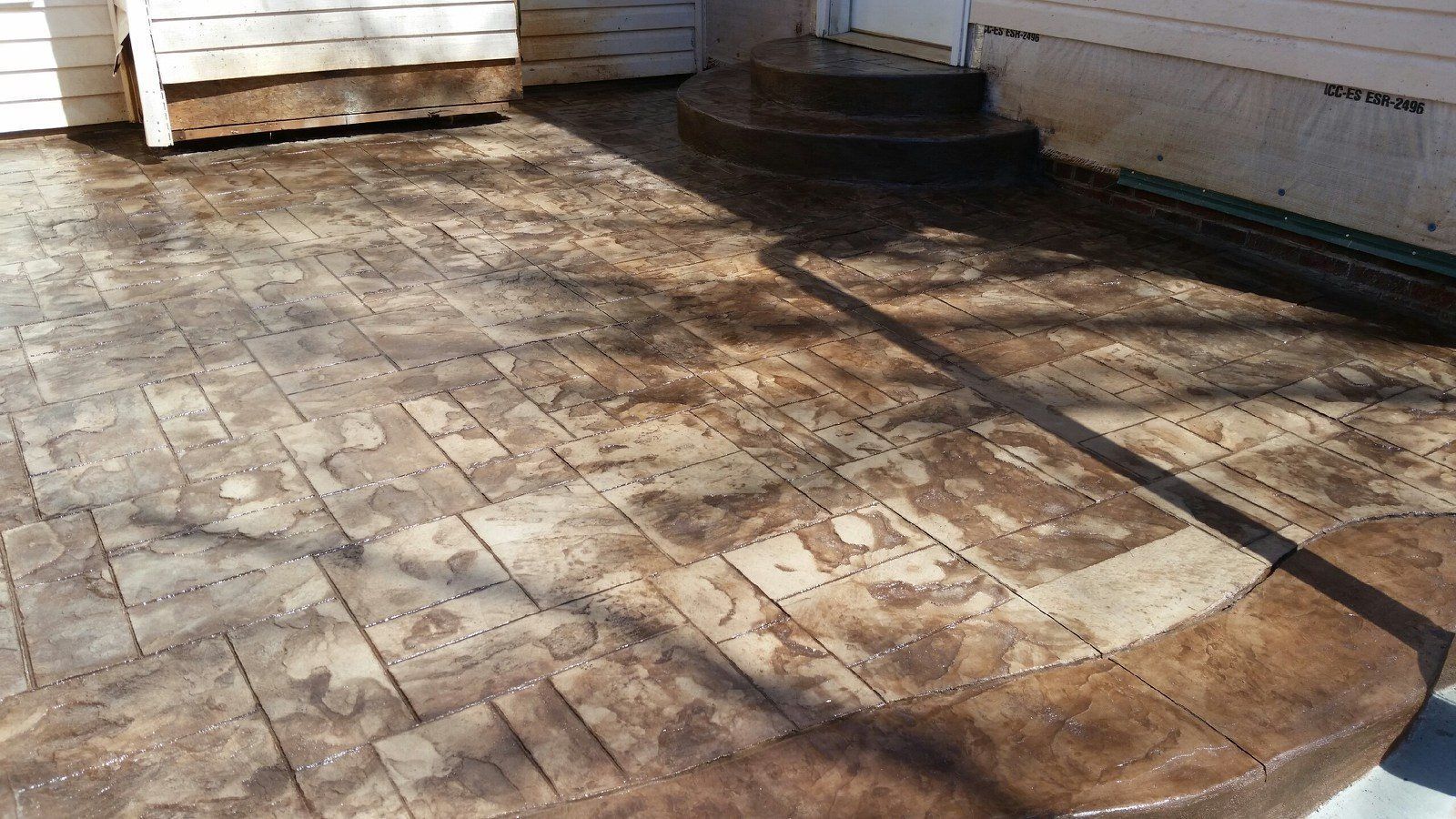 Brick patio with dark stains, near building and steps.