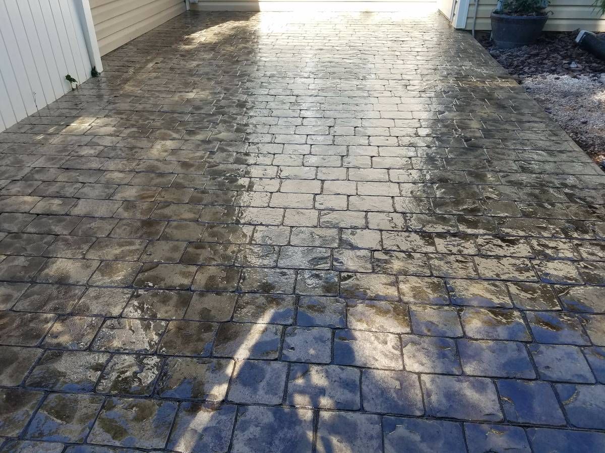 Wet, brick-patterned pavement in sunlight.
