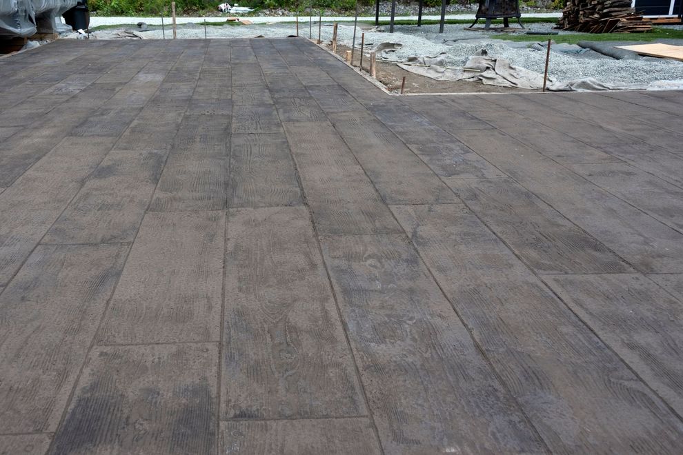 Concrete patio with a wood-plank design. Grey tones, construction setting.